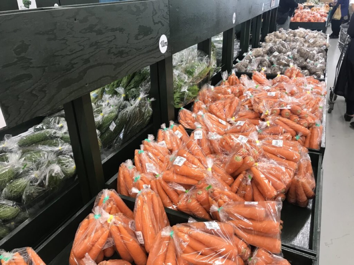 우루 마르셰의 나무 선반에 놓인 당근과 오이, 여주
