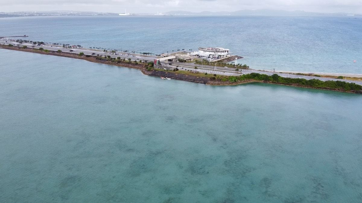 浅い海に築かれた海中道路と、その途中に立つ海の駅あやはし館を上空から見た様子