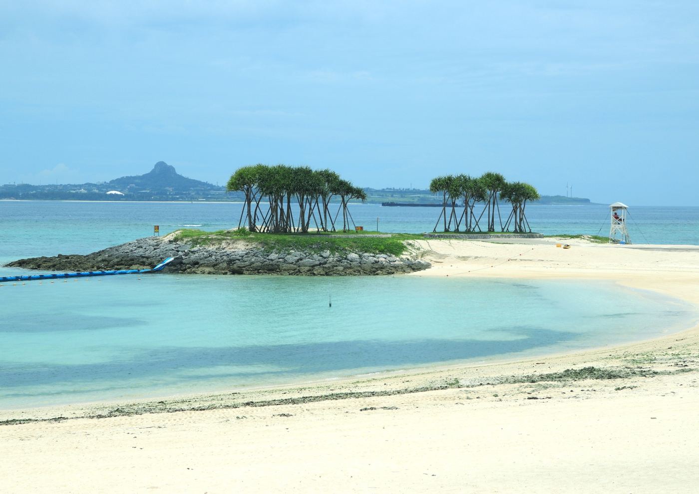 エメラルドビーチの砂浜と、松の木が生えた小島、遠くに伊江島