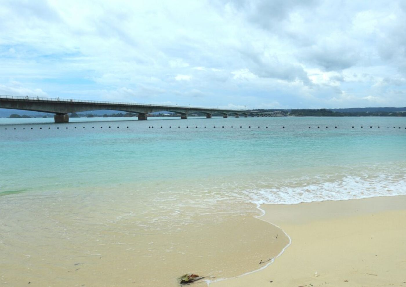 古宇利ビーチの砂浜から見た古宇利大橋と、透きとおった浅い海