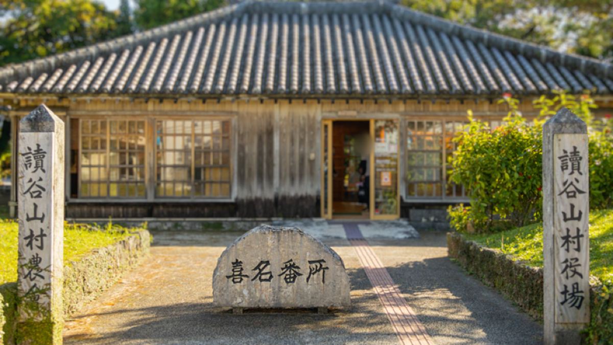 赤瓦の平屋を復元した道の駅喜名番所の正面と、讀谷山村役場と刻まれた石柱