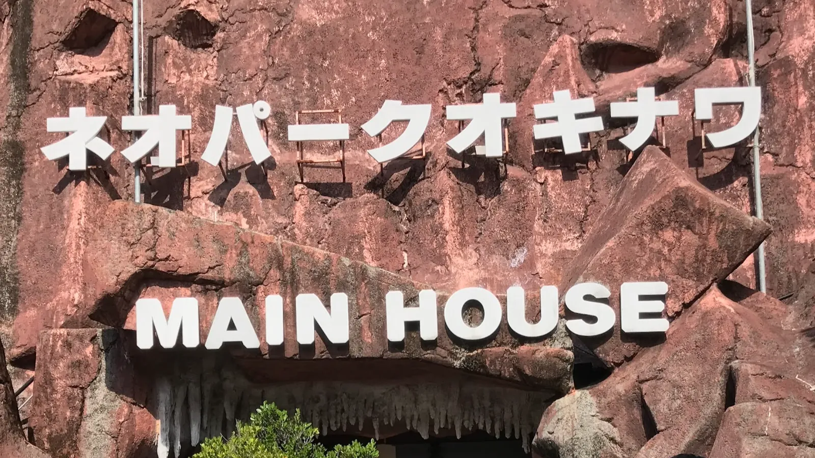 「ネオパークオキナワ MAIN HOUSE」と書かれた赤い壁の看板