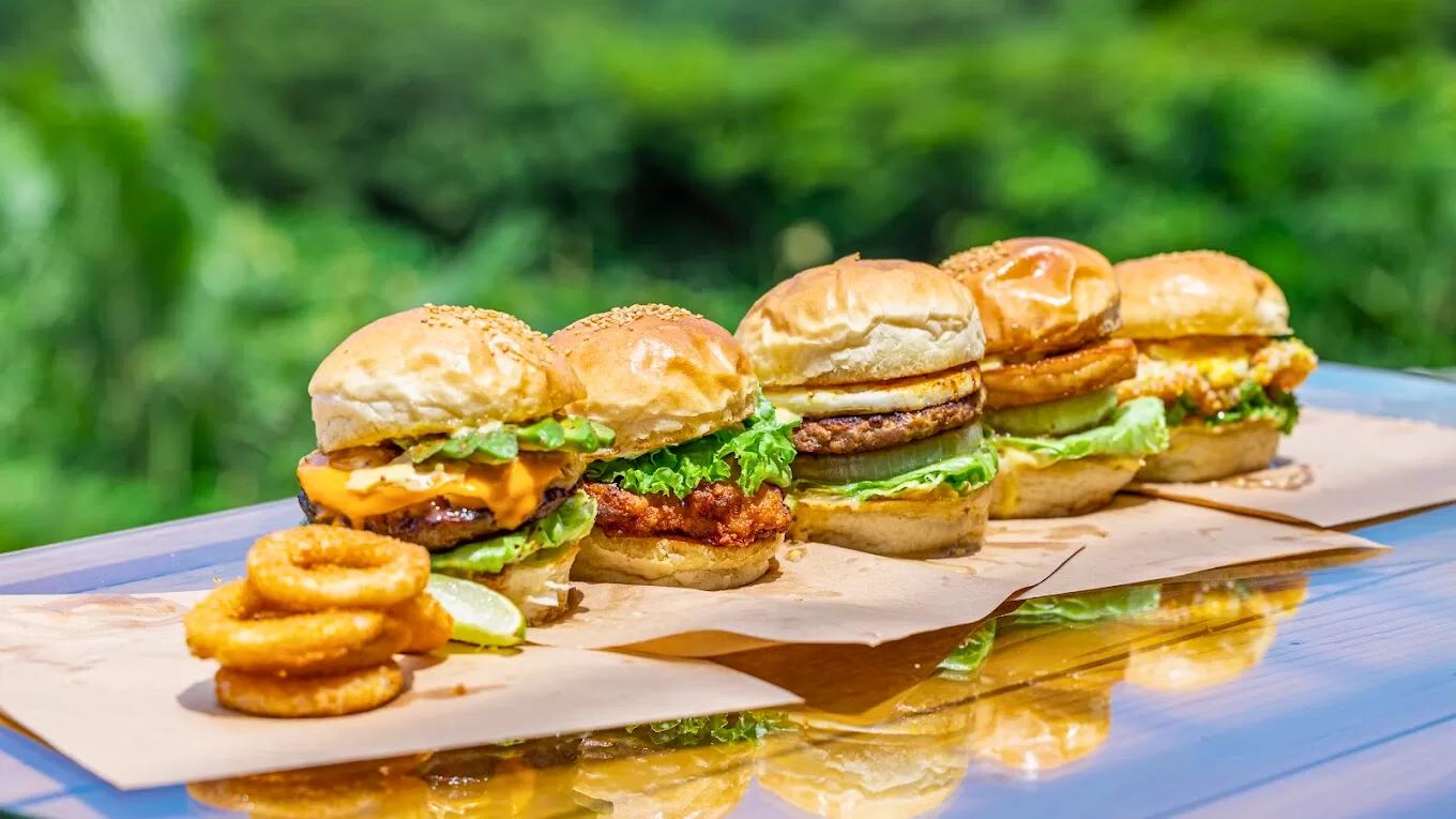 木のテーブルに並んだ5種類のミニバーガーとオニオンリング